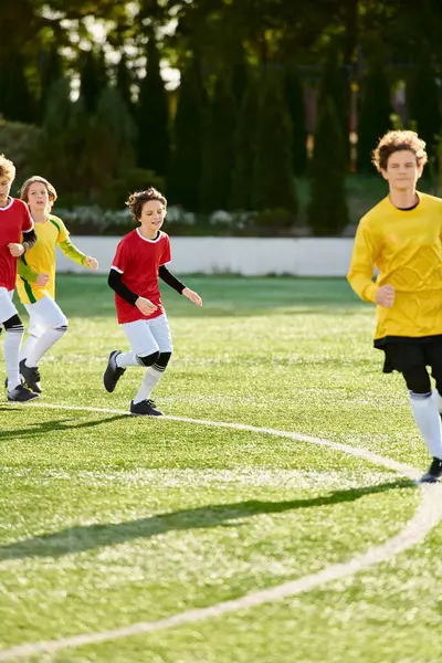 Un grupo de jóvenes enérgicos en camisetas de fútbol jugando apasionadamente un juego de fútbol en un campo de hierba. Están corriendo, pateando, pasando y anotando goles, mostrando trabajo en equipo y deportividad. - foto de stock