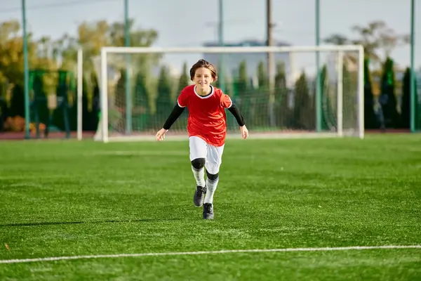 A young boy with boundless energy races across the green soccer field, his determination evident in every stride he takes towards the goalpost. — Stock Photo