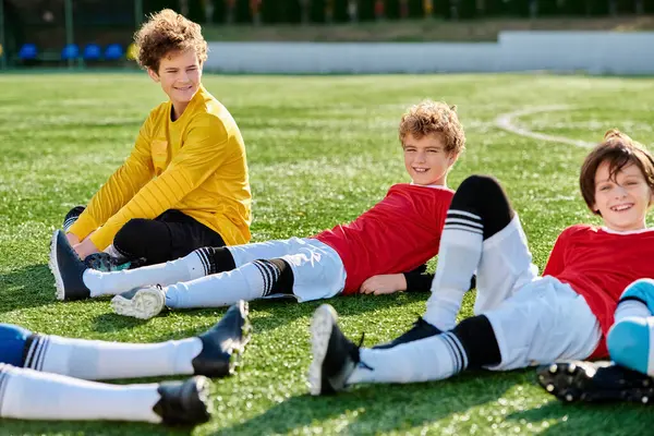 A group of youthful men seated on top of a verdant field, enjoying the serenity and beauty of nature. — Stock Photo