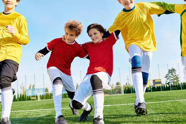 A group of young children in colorful jerseys are running, kicking, and passing a soccer ball on a grassy field under the bright sun. — Stock Photo