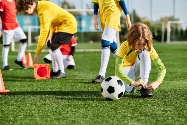Un grupo de niños pequeños que usan camisetas de colores están jugando enérgicamente un juego de fútbol en un campo. Están corriendo, pateando la pelota, y animando con emoción. - foto de stock
