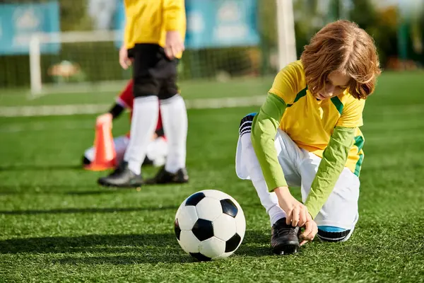 Una niña con coletas juega felizmente con una pelota de fútbol en un campo verde vibrante, pateando, goteando y practicando sus habilidades. - foto de stock