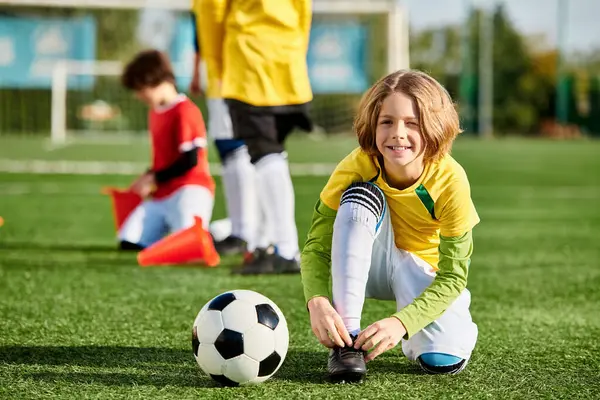 Una joven con una sonrisa brillante juega con una pelota de fútbol, pateando y goteando con entusiasmo en un campo de hierba en un día soleado. - foto de stock