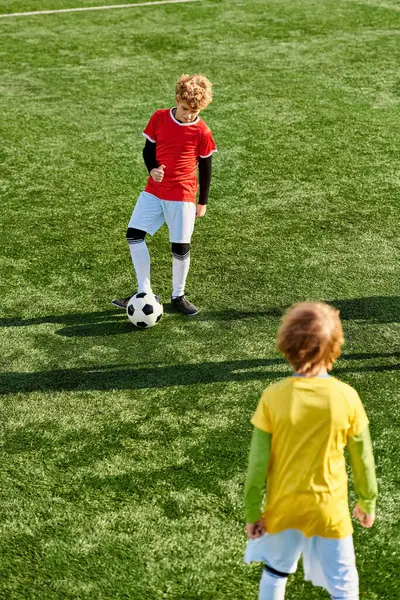 Мальчик энергично пинает футбольный мяч на пышном зеленом поле, демонстрируя свой талант и страсть к спорту.. — стоковое фото