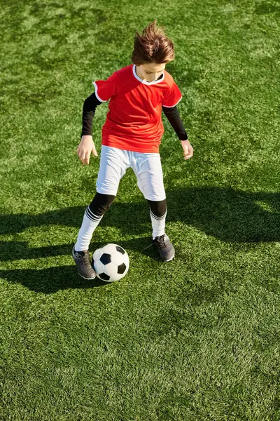 Um jovem rapaz está a chutar energicamente uma bola de futebol num campo verde. Sua concentração é evidente à medida que ele pratica suas habilidades, visando precisão e poder a cada chute. — Fotografia de Stock