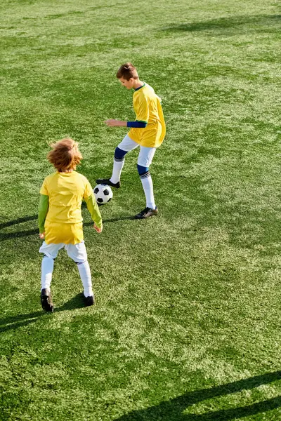 Eine lebhafte Szene spielt sich ab, als zwei junge Männer auf dem Spielfeld fröhlich um einen Fußball kicken und dabei ihr Können mit Leichtigkeit und Finesse zeigen.. — Stockfoto