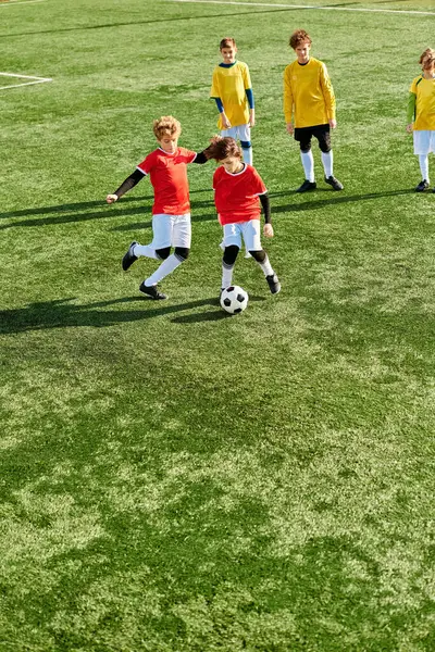 Un groupe de jeunes enfants jouant énergiquement à un jeu de football sur un terrain herbeux. Ils courent, dribblent, passent et donnent des coups de pied au ballon avec enthousiasme et travail d'équipe. — Photo de stock