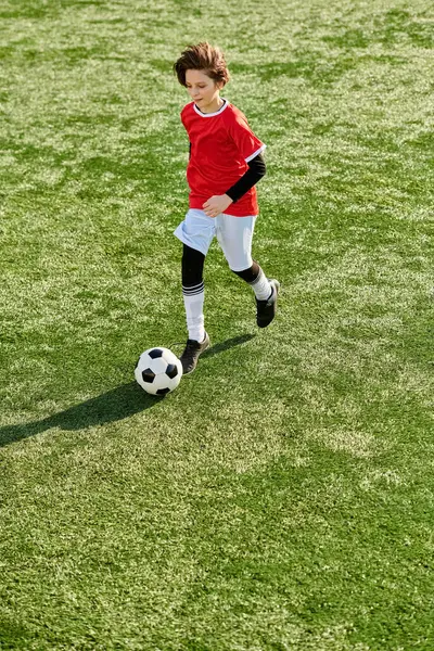 Um jovem chuta uma bola de futebol com determinação e habilidade em um campo verde exuberante, mostrando sua paixão pelo esporte. — Fotografia de Stock
