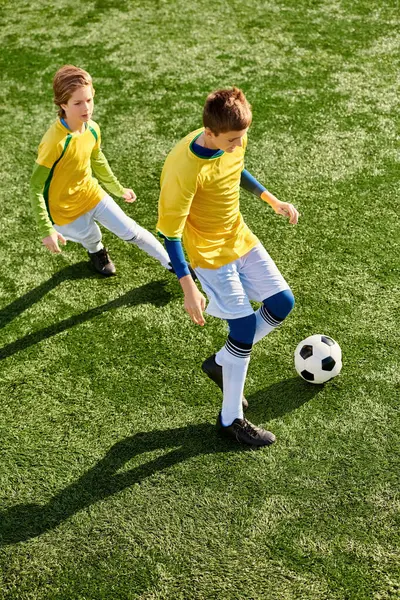 Two energetic young boys running on a vibrant green soccer field while kicking a soccer ball back and forth. — Stock Photo