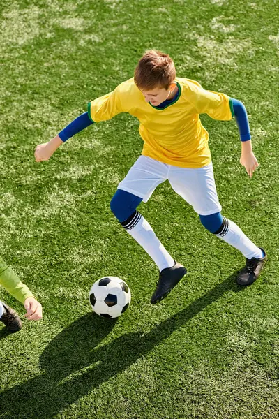 Dos jóvenes patean enérgicamente una pelota de fútbol de ida y vuelta en un campo de hierba. Sus rápidos movimientos y su hábil juego de pies muestran su pasión por el deporte mientras participan en un amistoso juego de fútbol.. - foto de stock