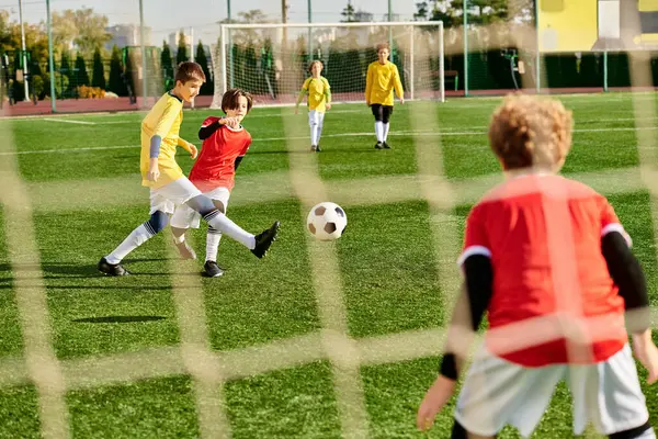 Um grupo animado de crianças pequenas jogando um jogo entusiasta de futebol, correndo, chutando e passando a bola com puro prazer e energia. — Fotografia de Stock