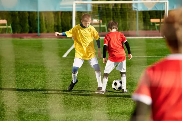 Zwei junge Kinder spielen begeistert ein Fußballspiel in einem Park, kicken den Ball auf dem Rasenplatz hin und her und genießen dabei einen freundschaftlichen Wettkampf. — Stockfoto