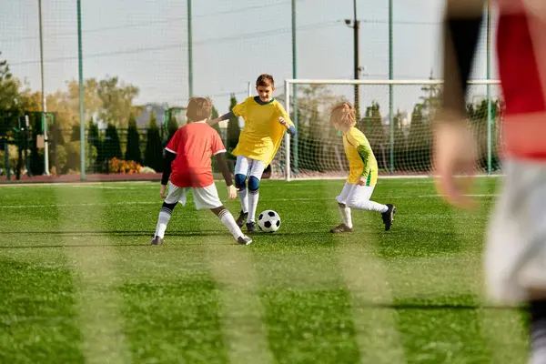 Un grupo de niños pequeños, llenos de energía y entusiasmo, jugando un intenso juego de fútbol en un campo de hierba. Están pateando, corriendo y pasando la pelota, mostrando trabajo en equipo y deportividad. - foto de stock