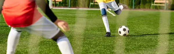 Мальчик, полный энергии, умело пинает футбольный мяч по зеленому полю. Он полностью контролирует мяч, демонстрируя отличную технику и сосредоточенность на тренировках.. — стоковое фото