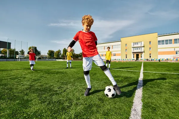 Талантливый мальчик умело пинает футбольный мяч по зеленому полю, демонстрируя свою ловкость и точность в спорте. — стоковое фото