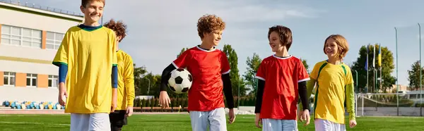 Um grupo de jovens, vestidos com equipamento de futebol, fica ombro a ombro em um campo de futebol. Eles parecem focados e prontos para jogar, com a grama verde e as balizas em segundo plano. — Fotografia de Stock