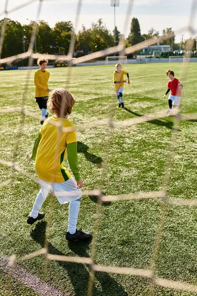 Eine Gruppe kleiner Kinder spielt an einem sonnigen Tag temperamentvoll Fußball. Sie rennen, treten und feuern sich gegenseitig an, während sie in einem Freundschaftsspiel gegeneinander antreten. — Stockfoto
