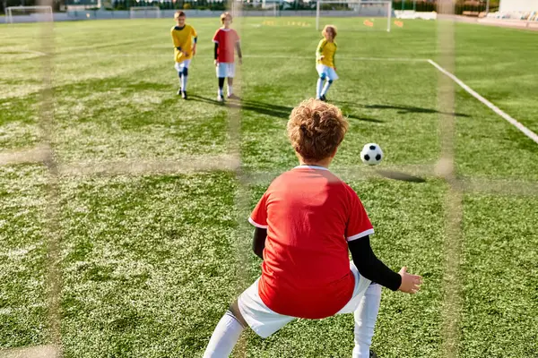 Um grupo de crianças pequenas energeticamente jogando um jogo de futebol, correndo, chutando, e passando a bola em um campo verde. — Fotografia de Stock