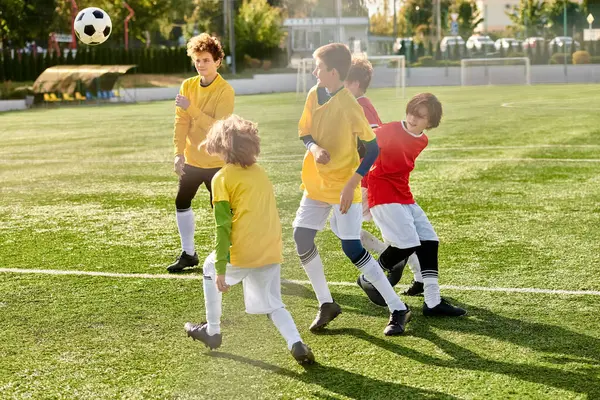 Un groupe de jeunes enfants jouant avec enthousiasme à un jeu de football. Habillés de maillots colorés, ils dégoulinent la balle, passent et tirent vers le but, mettant en valeur leur travail d'équipe et leurs compétences sur le terrain. — Photo de stock