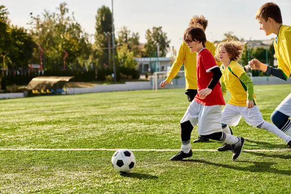 Eine Gruppe begeisterter Kleinkinder spielte auf einem Rasenplatz ein freundschaftliches Fußballspiel. Sie rennen, treten und geben den Ball weiter, während sie lachen und sich amüsieren. — Stockfoto