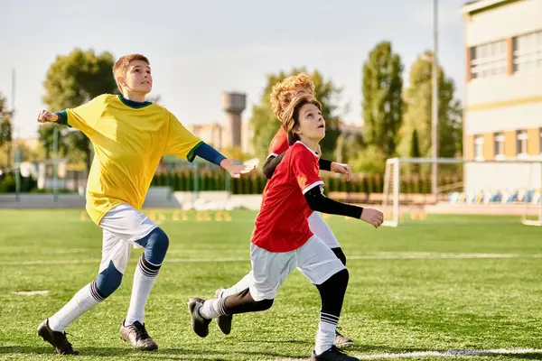 Un animado grupo de jóvenes participan en un intenso juego de fútbol, mostrando su habilidad, agilidad y trabajo en equipo en el campo mientras persiguen la pelota y se esfuerzan por superar a sus oponentes. - foto de stock
