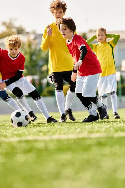 Un groupe d'enfants enthousiastes de différents âges jouant au soccer sur un terrain herbeux, donnant des coups de pied au ballon, courant et riant tout en profitant d'un jeu amical ensemble. — Photo de stock