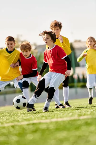 Un grupo de enérgicos niños pequeños jugando con entusiasmo un juego de fútbol en un campo de hierba. Están pateando una bola colorida, corriendo, riéndose y animándose mutuamente.. - foto de stock