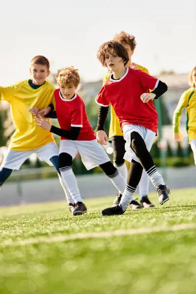 Un groupe de jeunes enfants sont immergés dans un jeu animé de football, de course, de coups de pied et de passer le ballon avec enthousiasme et travail d'équipe sur un terrain herbeux. — Photo de stock