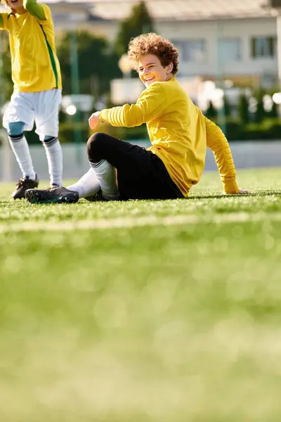 Молодий чоловік насолоджується миттю роздумів, сидячи на землі поруч з футбольним м'ячем. — стокове фото