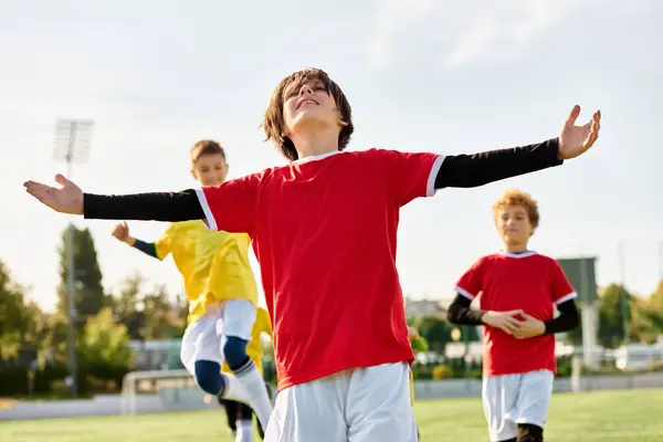 Un vivace gruppo di giovani impegnati in un gioco competitivo di calcio, corsa, calci, e passando la palla su un campo di erba sotto il sole luminoso. — Foto stock