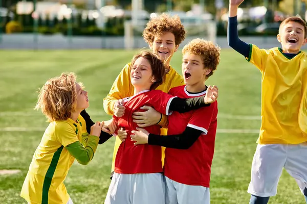 Un grupo de enérgicos niños pequeños están de pie triunfalmente en la cima de un campo de fútbol, exudando emoción y alegría después de un partido. Sus rostros brillan de orgullo mientras celebran juntos su victoria. - foto de stock