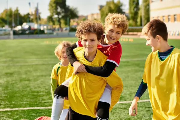 Un gruppo di ragazzi si erge trionfalmente su un campo da calcio, festeggiando la loro vittoria con sorrisi e cinque dopo una partita competitiva. — Foto stock