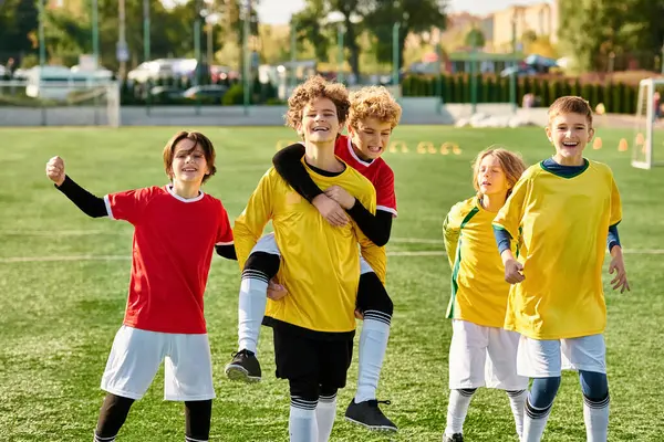 A group of young men celebrate their victory by standing triumphantly on top of a soccer field, enjoying the moment of accomplishment and camaraderie. — Stock Photo