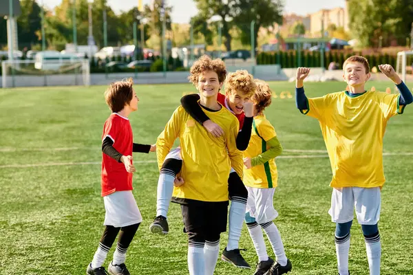 Група молодих хлопчиків стоїть тріумфально на вершині ретельно продуманого футбольного поля, їх обличчя б'ються з задоволенням і гордістю після успішного матчу.. — стокове фото