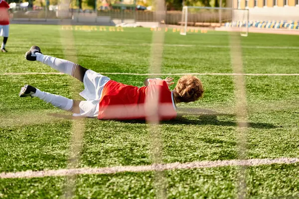 Un ragazzo gioca energicamente a calcio su un campo verde, indossando una maglia e dribbling la palla. Dimostra abilità e passione mentre si muove verso la meta, circondato dalla folla festante. — Foto stock