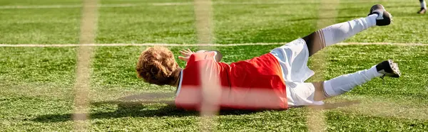 Una persona con ropa casual tendida en el suelo, luciendo relajada, al lado de una pelota de fútbol. El sol brilla intensamente, proyectando sombras en el suelo. La persona parece estar tomando un momento para descansar y disfrutar de la atmósfera pacífica. - foto de stock