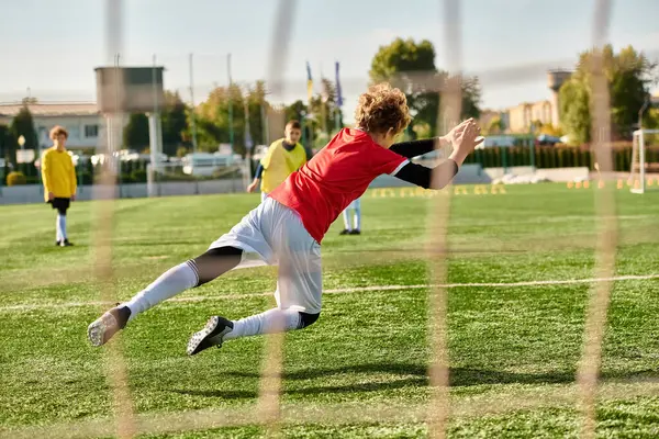 Un giovane uomo, pieno di determinazione, calcia un pallone da calcio attraverso un vasto campo. Il suo corpo in movimento, la palla che vola nell'aria, catturando l'essenza dell'atletismo e dell'abilità nel bellissimo gioco. — Foto stock