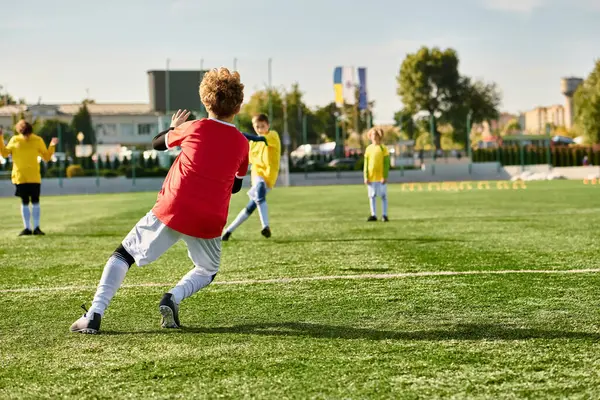 Un groupe de jeunes hommes engagés dans un jeu intense de football sur un terrain vert. Ils courent, donnent des coups de pied et passent le ballon avec beaucoup d'habileté et de travail d'équipe, le tout dans un esprit de compétition et de plaisir.. — Photo de stock
