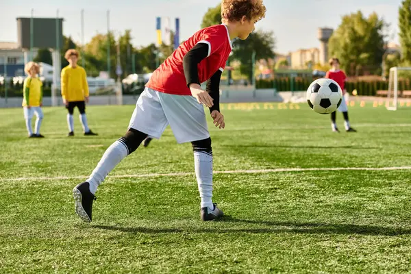 Мальчик, пинающий футбольный мяч на травяном поле, проявляющий решимость и мастерство в игре. — стоковое фото