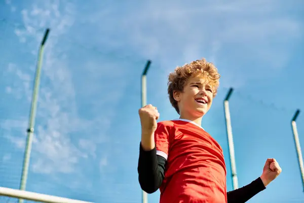 Um menino de camisa vermelha vibrante segura com confiança um taco de beisebol, pronto para balançar. Sua expressão focada e forte aderência indicam sua paixão pelo esporte. — Fotografia de Stock