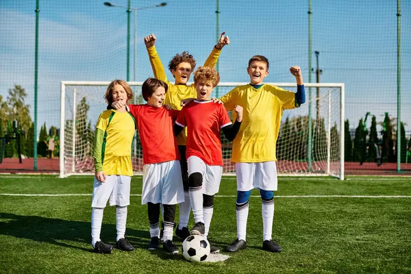 Eine muntere Gruppe junger Jungen steht triumphierend auf einem pulsierenden Fußballplatz und schwelgt in ihrem Sieg unter der goldenen Sonne. — Stockfoto