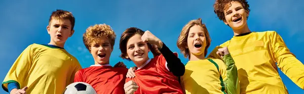 Разнообразная группа молодых людей, стоящих рядом друг с другом, держащих футбольный мяч, демонстрирующих командную работу, дружбу и общую страсть к игре. — стоковое фото