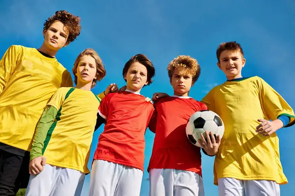 Un gruppo di giovani uomini in piedi strettamente insieme, tenendo un pallone da calcio, mettendo in mostra il lavoro di squadra e cameratismo. — Foto stock