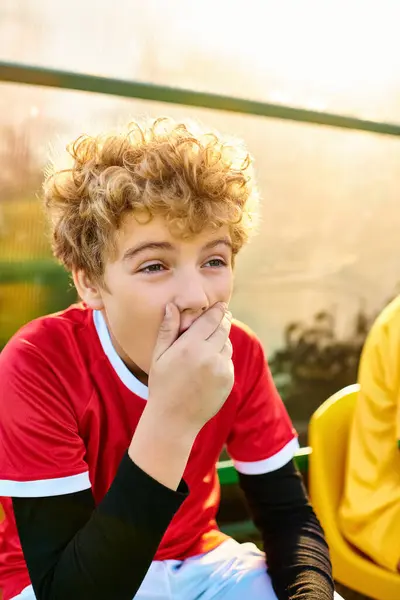 Ein kleiner Junge mit nachdenklichem Gesichtsausdruck sitzt auf einer Bank, die Hand sanft auf den Mund gelegt. — Stockfoto