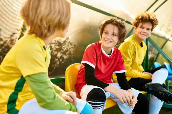 A group of young boys sit closely together, creating a circle of camaraderie. They engage in conversation, laughter, and friendly gestures, showcasing the bond between friends. — Stock Photo