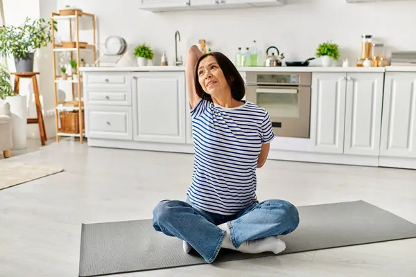 Mujer en ropa de casa acogedora practicando yoga en una estera en una cocina. - foto de stock