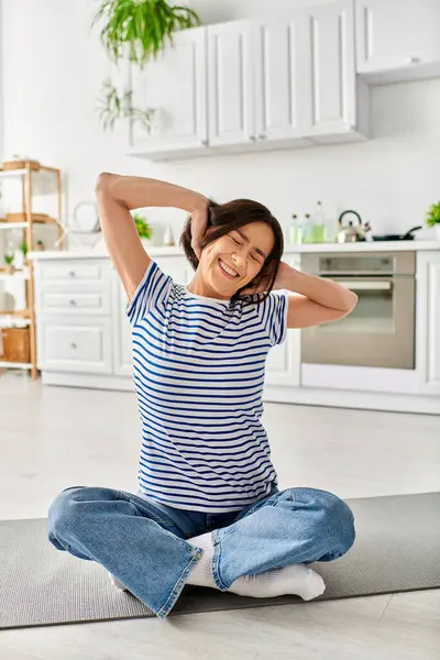 Mature woman in cozy homewear sits on floor, arms behind head, in peaceful contemplation. — Stock Photo
