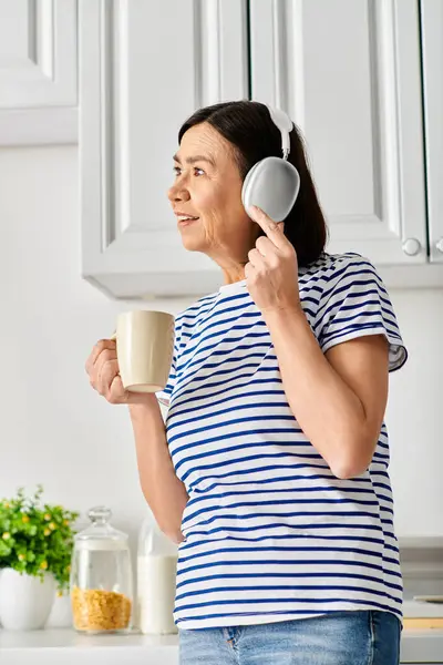 A woman in cozy homewear holding a cup and hair dryer. — Stock Photo