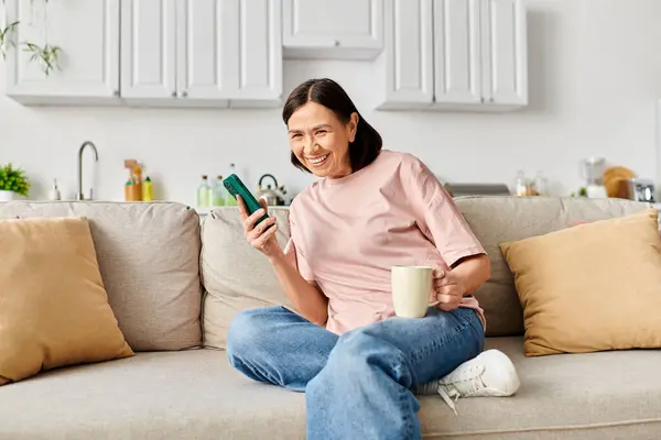 Mulher madura em casa aconchegante desfrutando de momento tranquilo no sofá com celular. — Fotografia de Stock