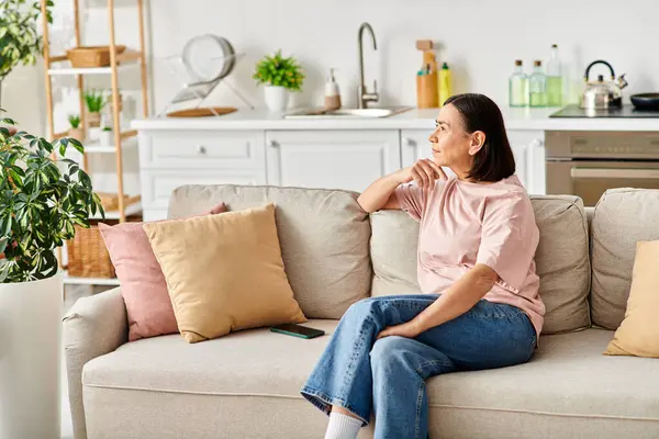 Eine reife Frau entspannt sich auf einer Couch in ihrem gemütlichen Wohnzimmer. — Stockfoto